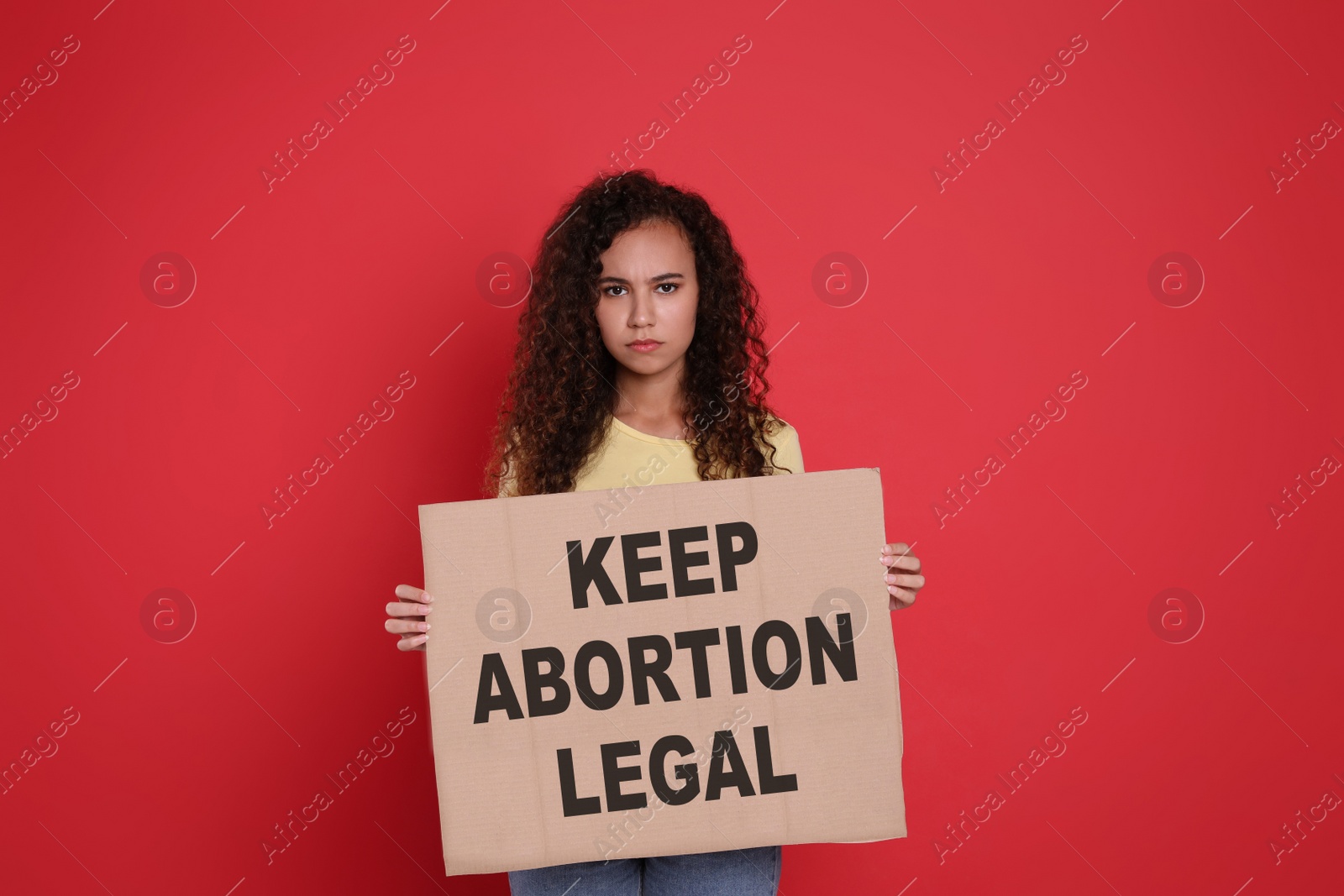 Image of African American woman holding placard with phrase Keep Abortion Legal on red background. Abortion protest