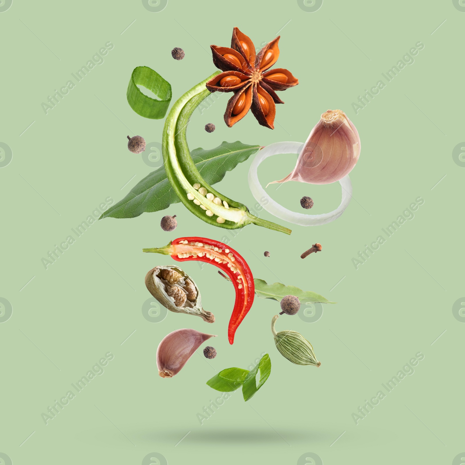 Image of Different spices falling on light green background