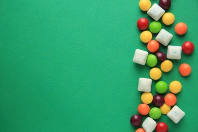 Different tasty chewing gums on green background, flat lay. Space for text