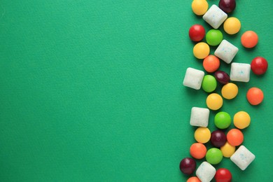 Photo of Different tasty chewing gums on green background, flat lay. Space for text