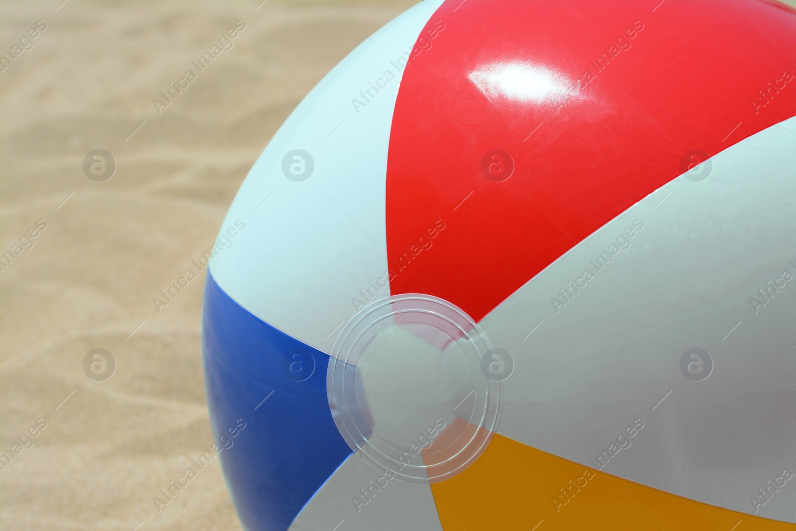 Photo of Colorful beach ball on sand, closeup view