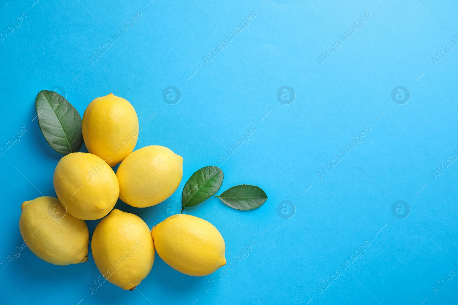 Photo of Fresh lemons and leaves on blue background, flat lay. Space for text