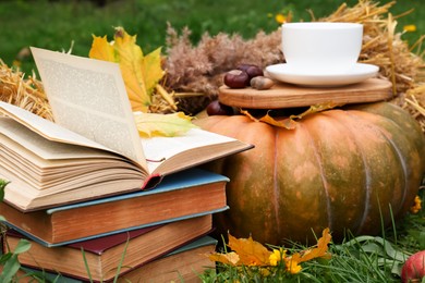 Photo of Books, pumpkin and cup of tea outdoors. Autumn season
