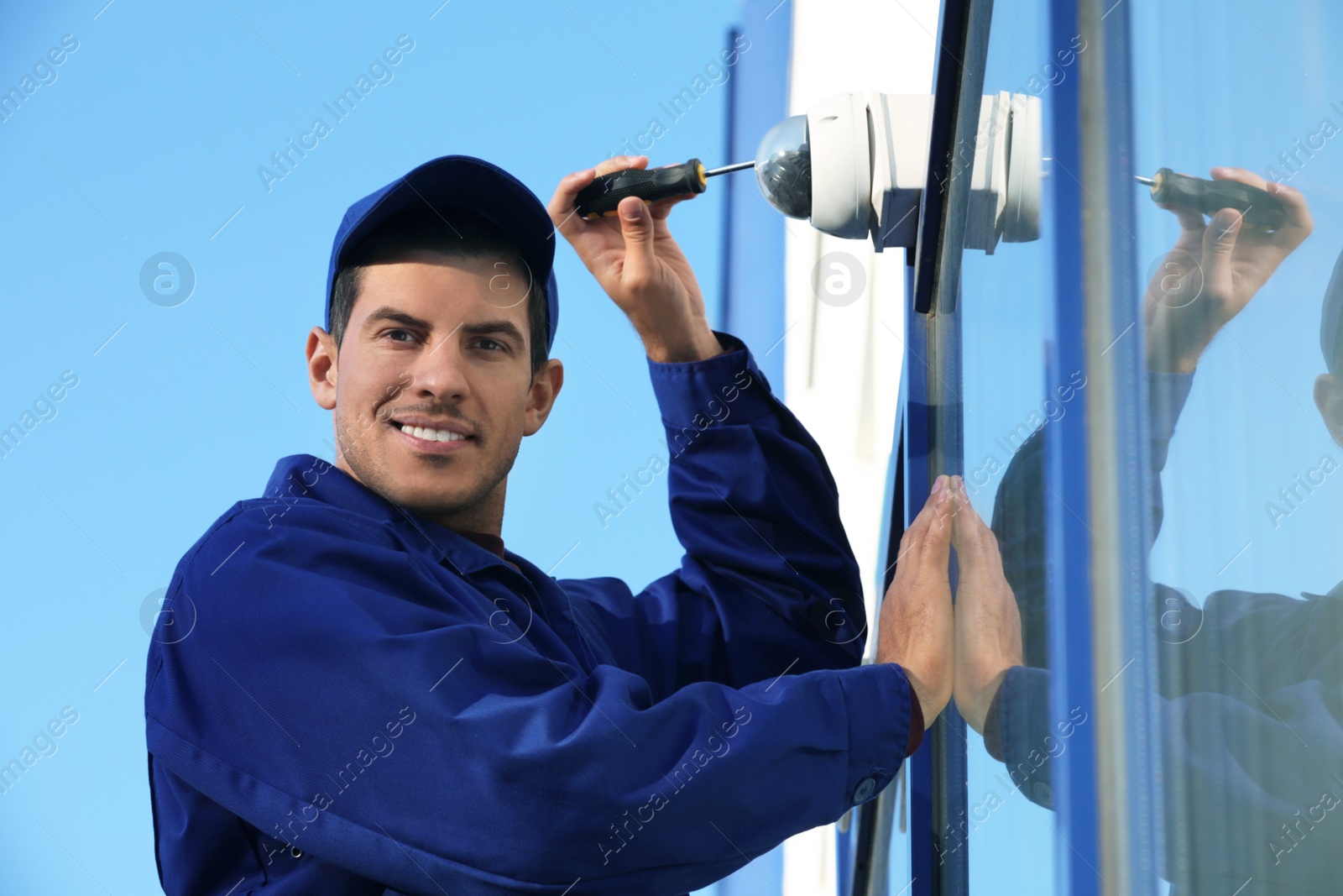 Photo of Technician installing CCTV camera on wall outdoors