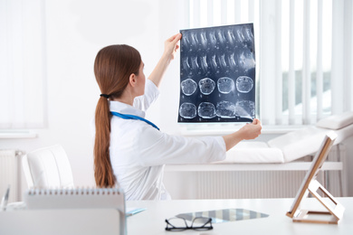 Orthopedist examining X-ray picture at desk in clinic