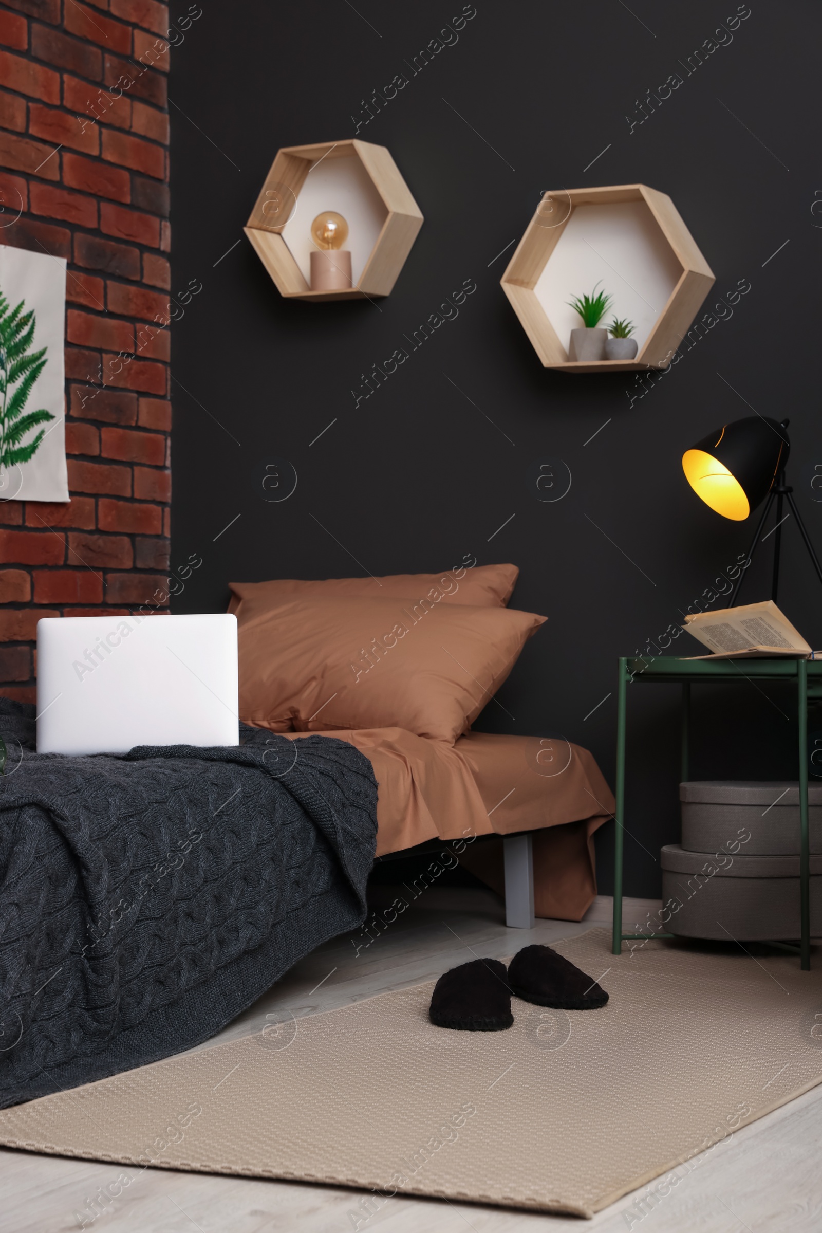 Photo of Stylish teenager's room with laptop on bed near brick wall