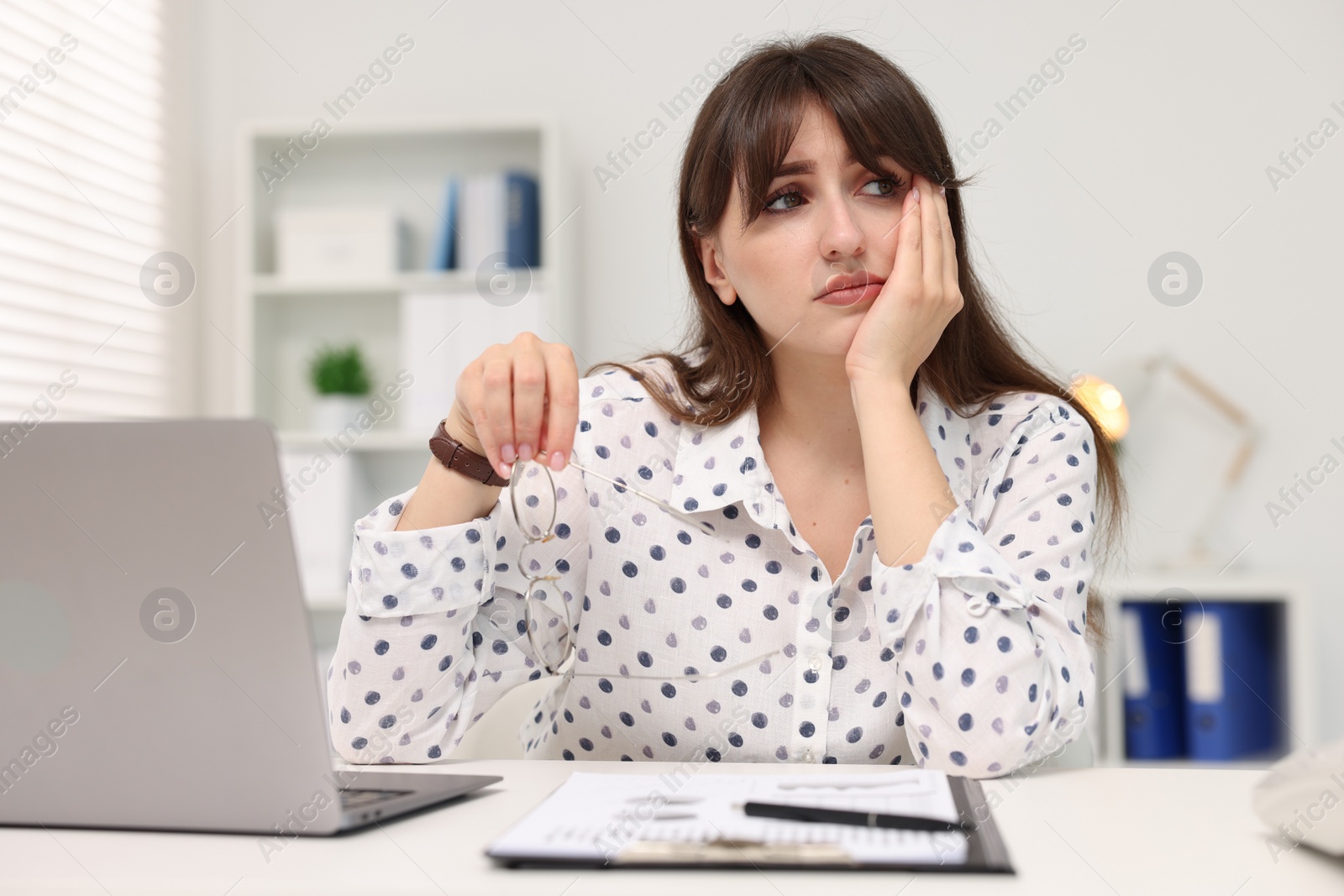 Photo of Overwhelmed woman sitting at table with laptop in office