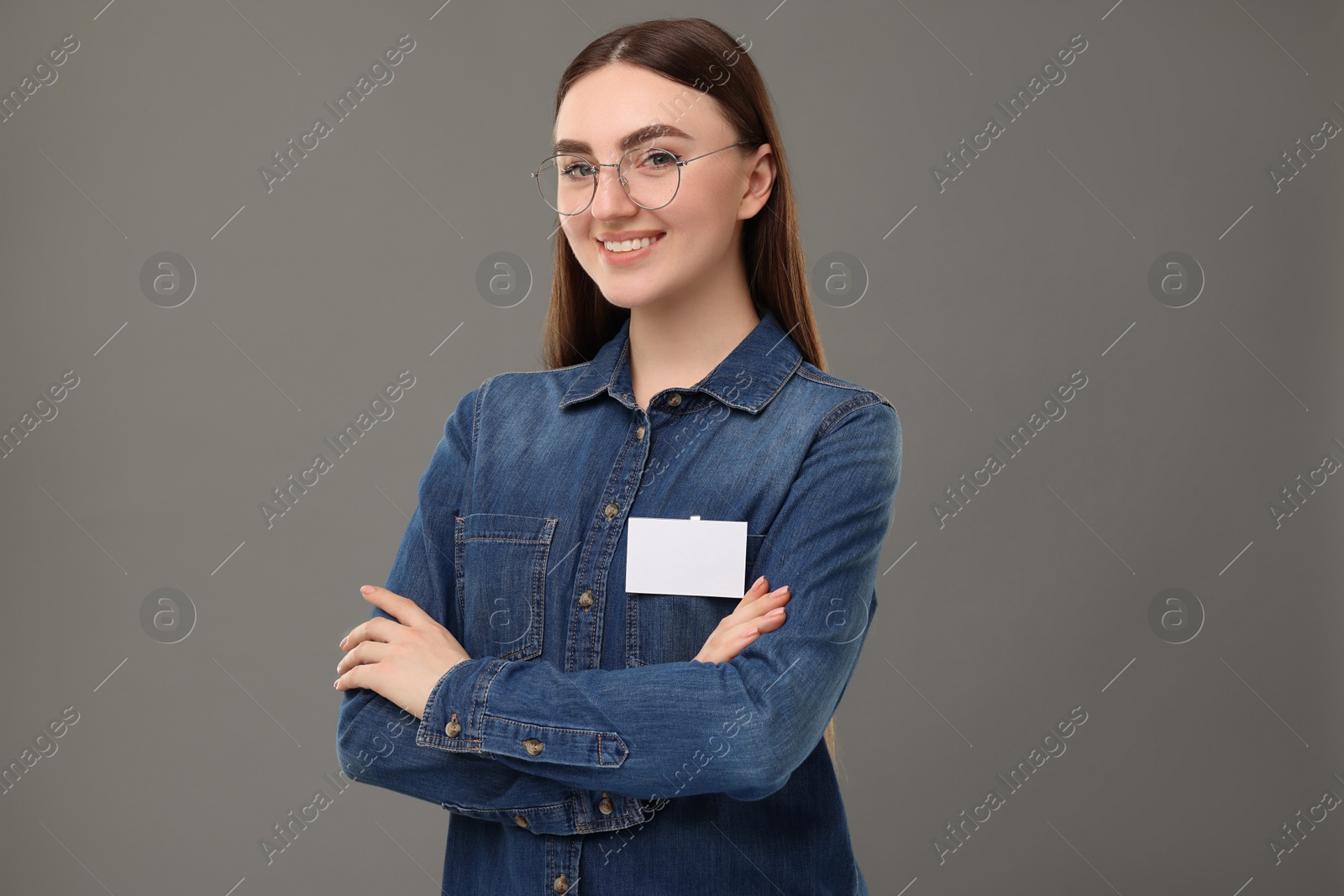 Photo of Happy woman with blank badge on grey background