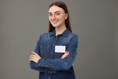 Happy woman with blank badge on grey background