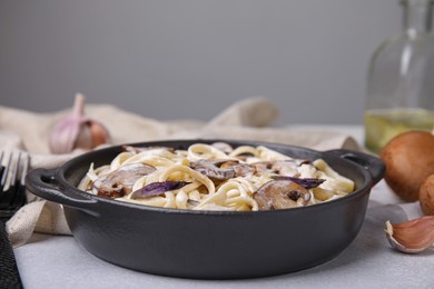 Photo of Delicious pasta with mushrooms on grey table, closeup