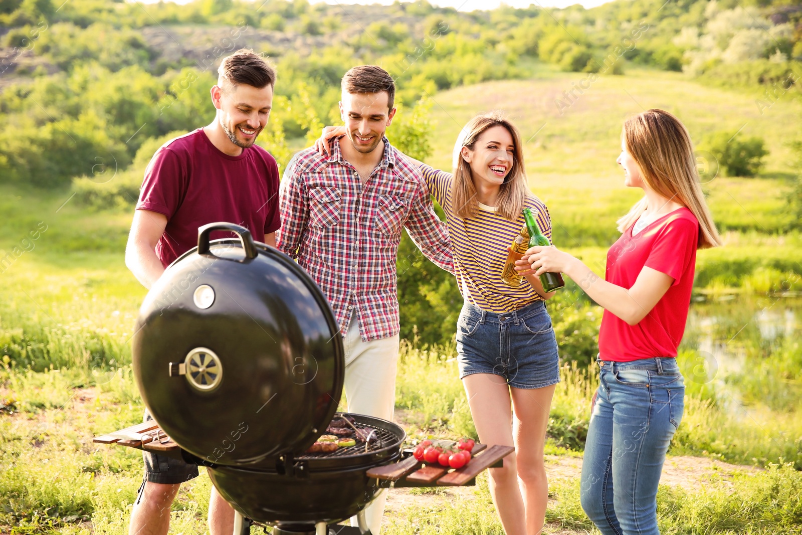 Photo of Young people having barbecue in wilderness. Camping season