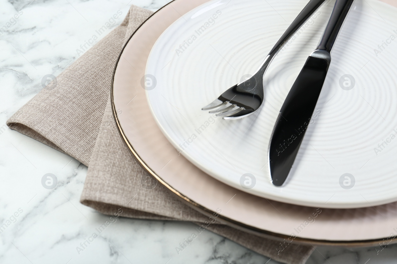 Photo of Clean plates, cutlery and napkin on table, closeup