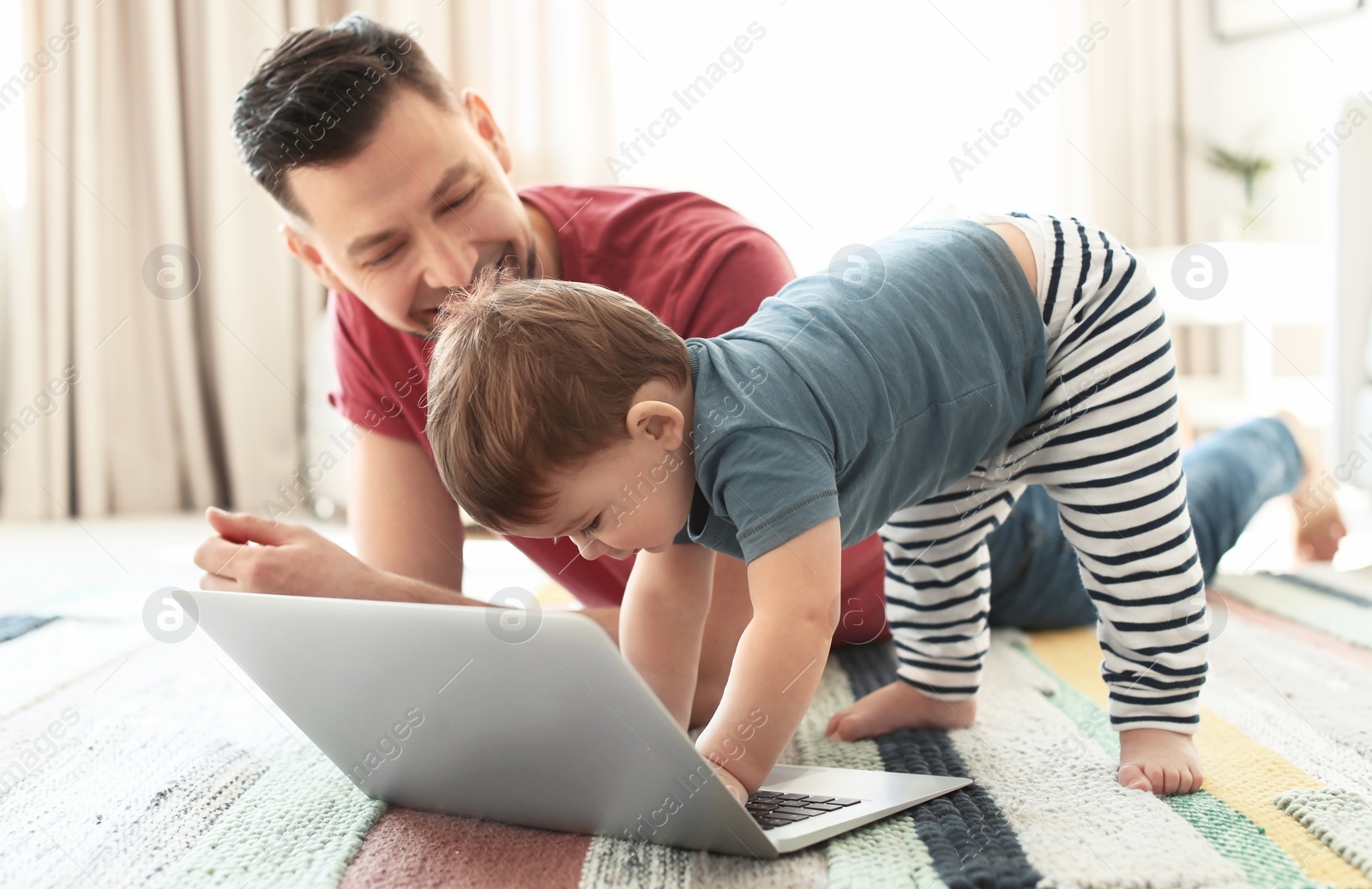 Photo of Dad and his son with laptop on carpet at home
