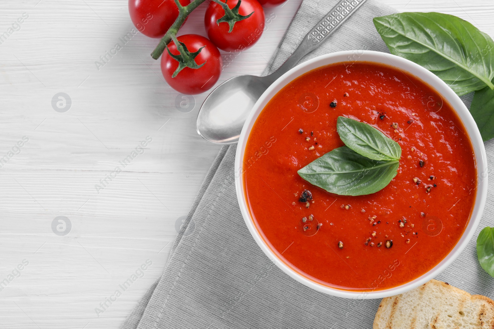 Photo of Flat lay composition with delicious tomato cream soup in bowl on white wooden table. Space for text