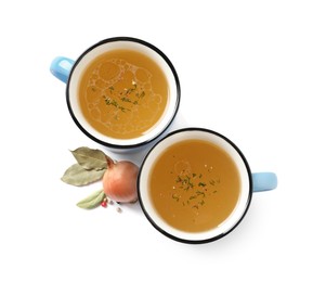 Hot delicious bouillon in cups and ingredients on white background, top view