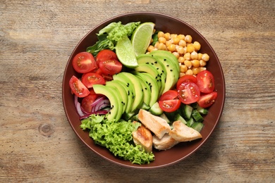 Photo of Delicious avocado salad with fried chicken on wooden table, top view