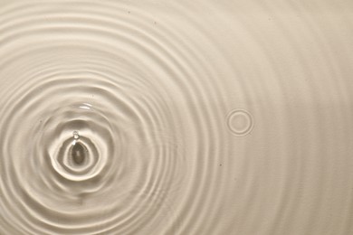 Rippled surface of clear water on beige background, top view
