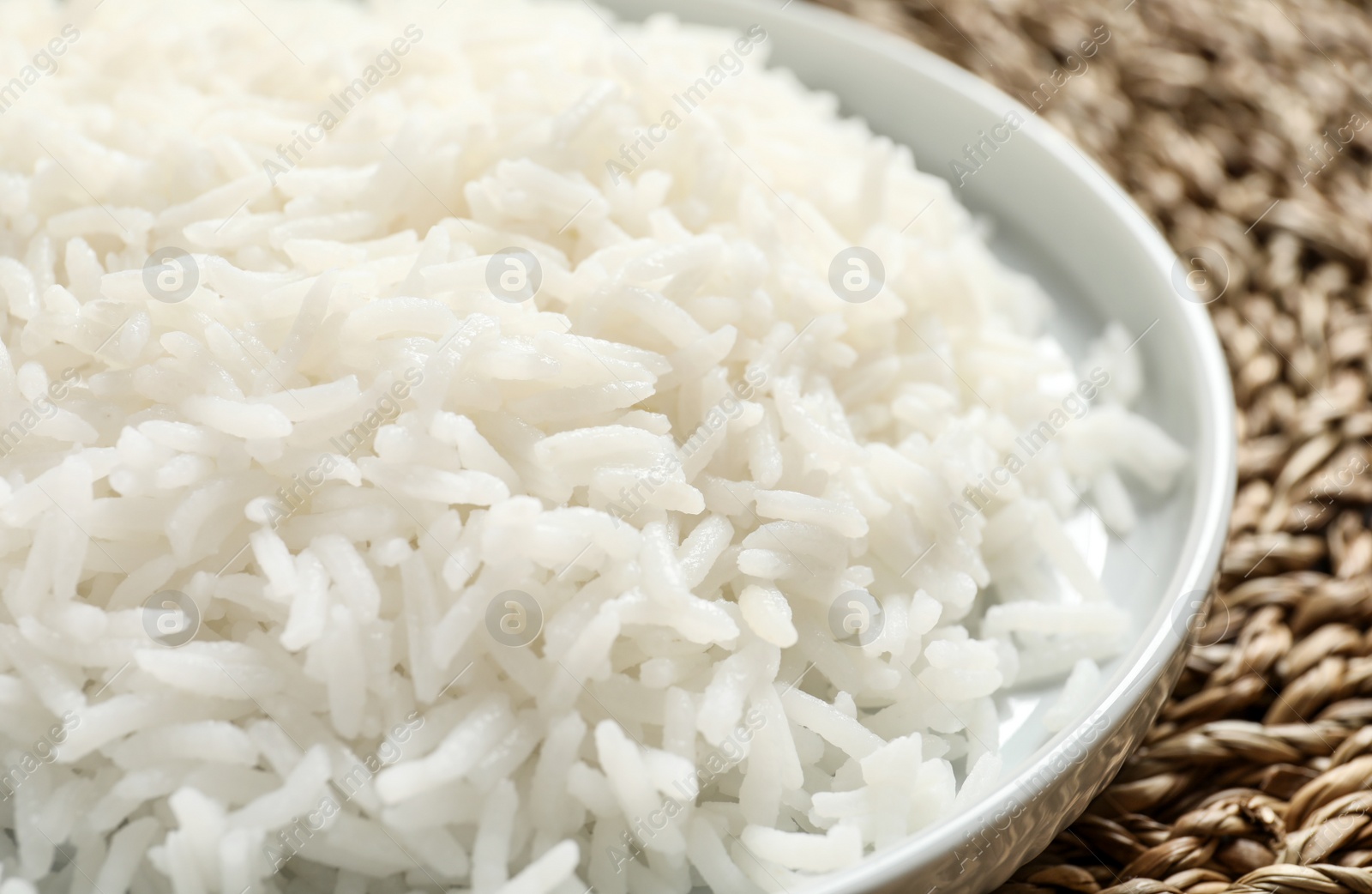 Photo of Plate of tasty cooked rice on wicker mat, closeup