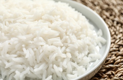 Photo of Plate of tasty cooked rice on wicker mat, closeup