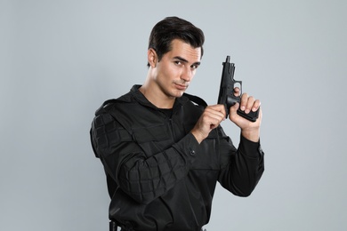 Photo of Male security guard in uniform with gun on grey background