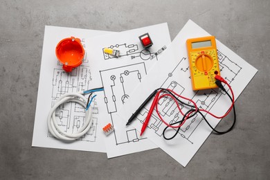 Photo of Wiring diagrams, digital multimeter and other electrician's equipment on grey table, flat lay