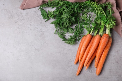 Photo of Bunch of carrots on stone background, top view. Space for text