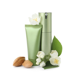 Cosmetic products, almond nuts and flowers on white background