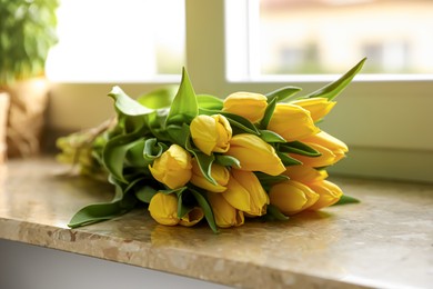 Photo of Bunch of beautiful yellow tulip flowers on windowsill, closeup