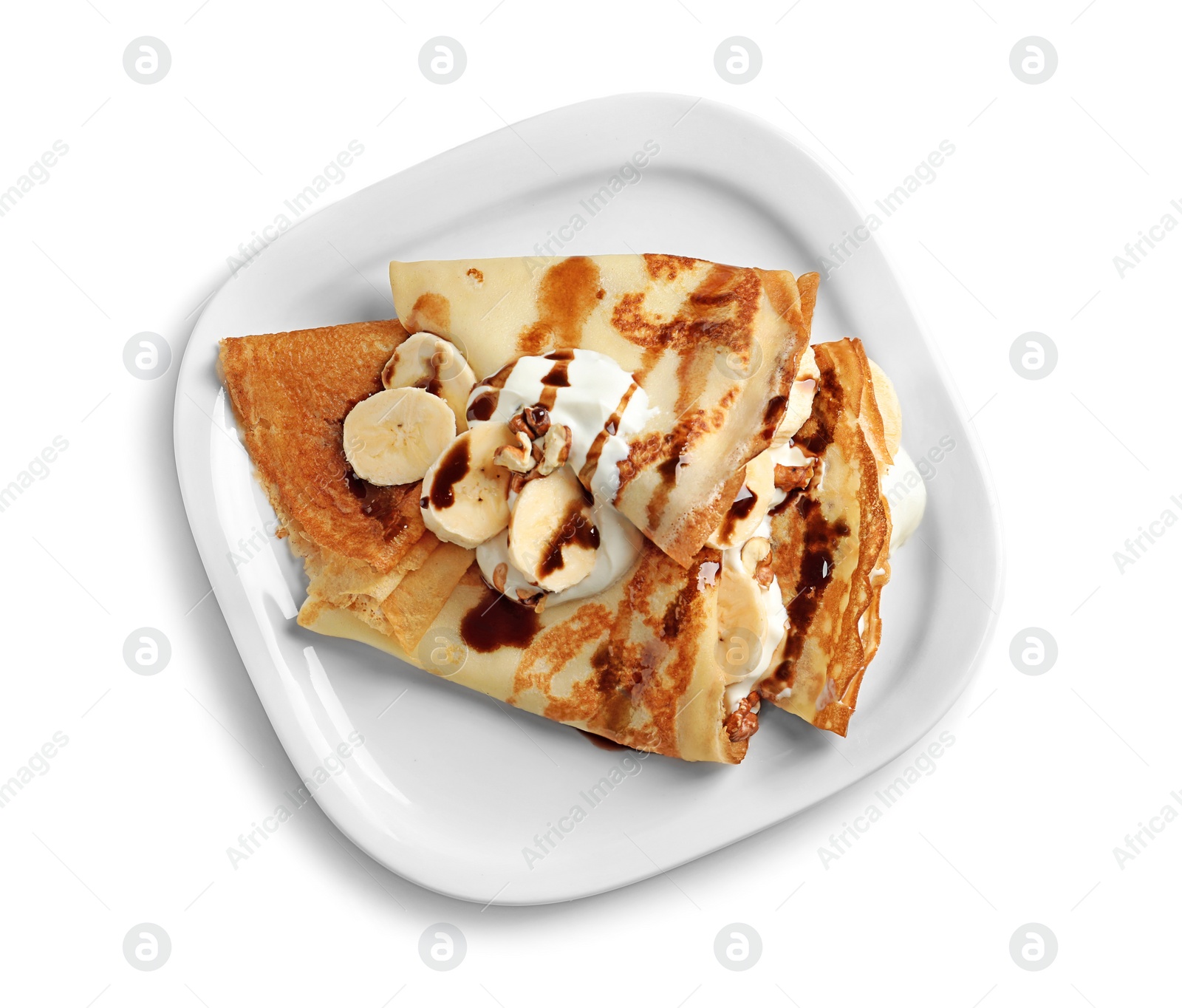 Photo of Thin pancakes with chocolate syrup, cream and banana on plate against white background, top view