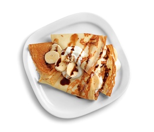 Photo of Thin pancakes with chocolate syrup, cream and banana on plate against white background, top view