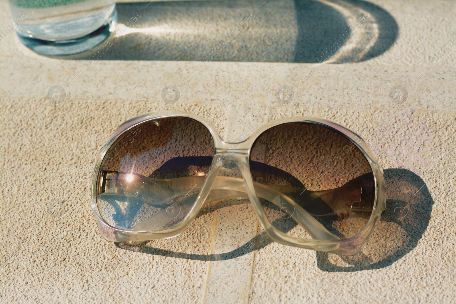 Photo of Stylish sunglasses on stone surface, closeup. Beach accessory