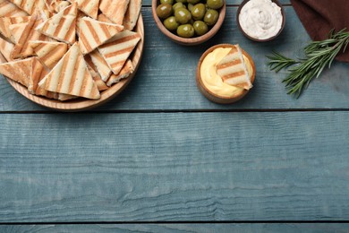 Photo of Delicious pita chips on blue wooden table, flat lay. Space for text