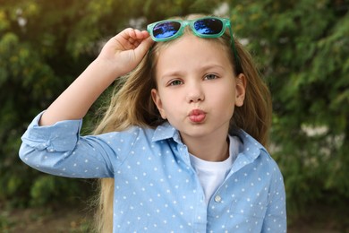 Photo of Girl wearing stylish sunglasses near spruce trees outdoors