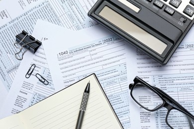 Photo of Calculator, pen, notebook and glasses on documents, flat lay. Tax accounting