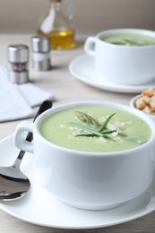 Photo of Delicious asparagus soup with green onion served on white wooden table