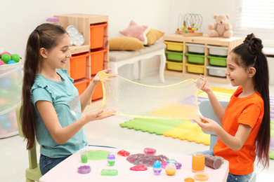 Happy girls playing with slime in room