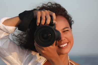 Photo of African American photographer taking photo with professional camera outdoors