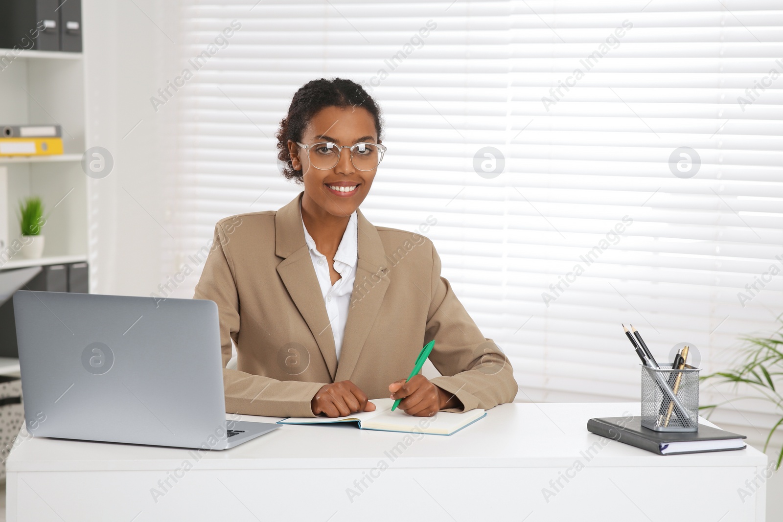 Photo of African American intern working at white table in office