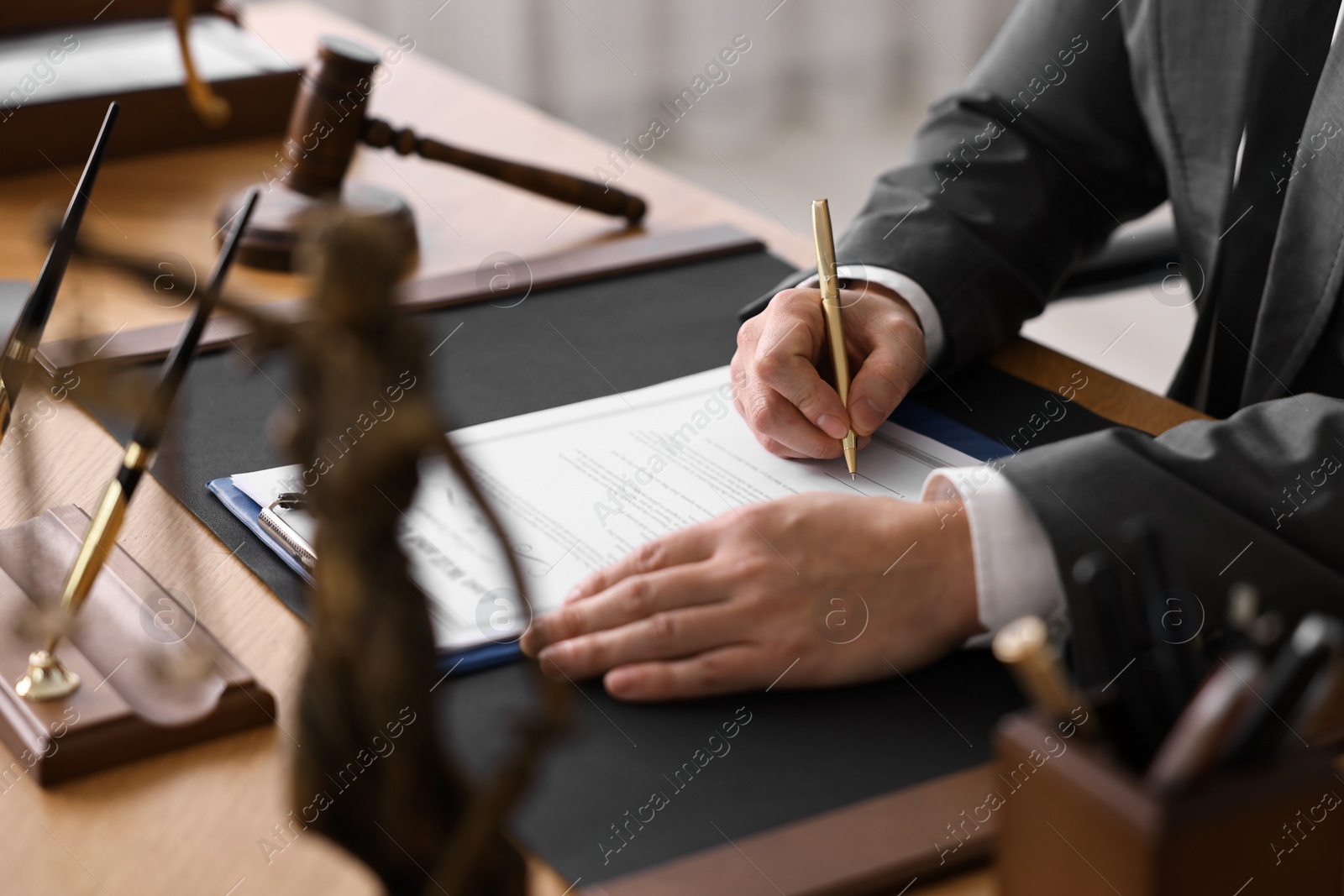 Photo of Notary writing notes at wooden table in office, closeup