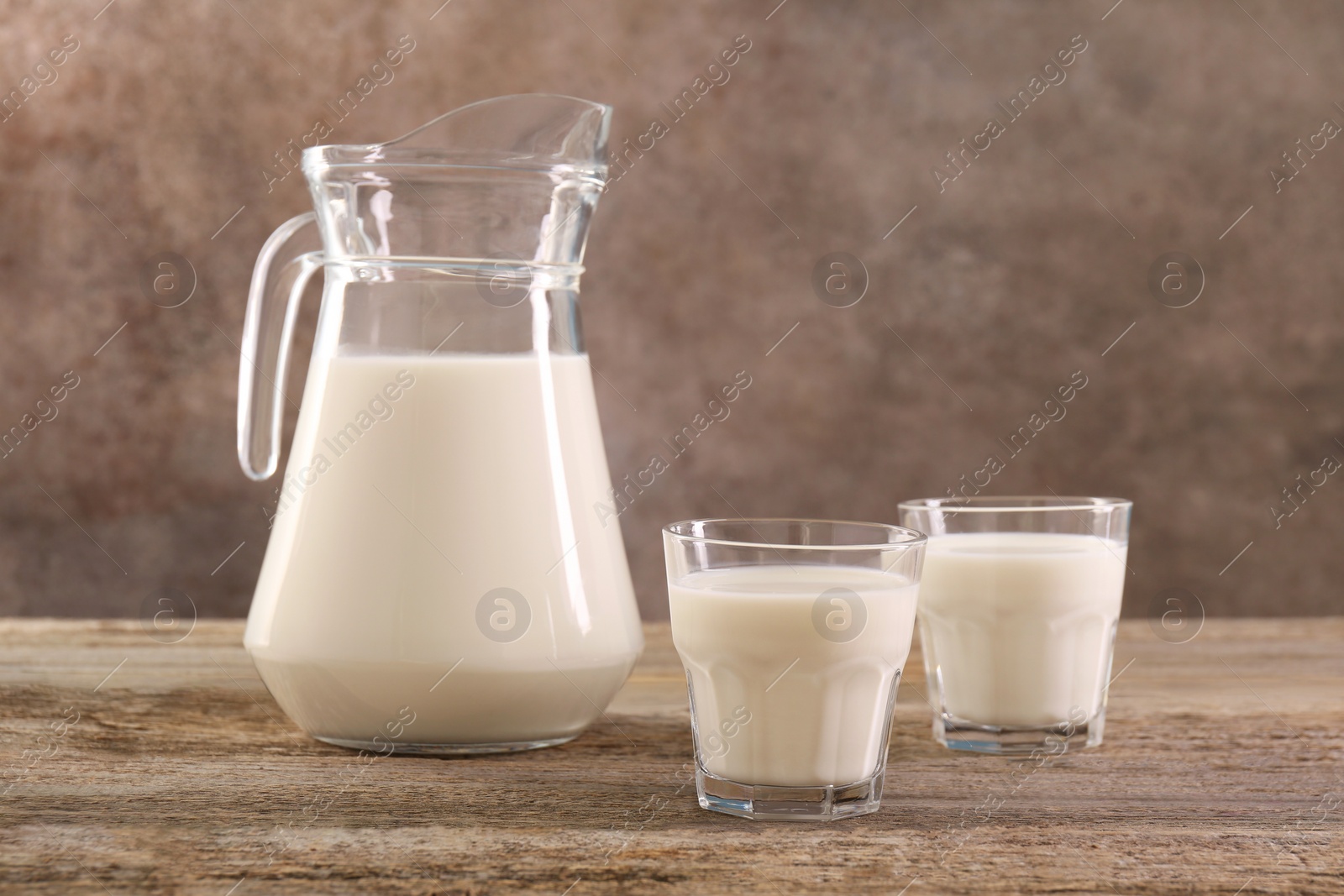 Photo of Jug and glasses of fresh milk on wooden table