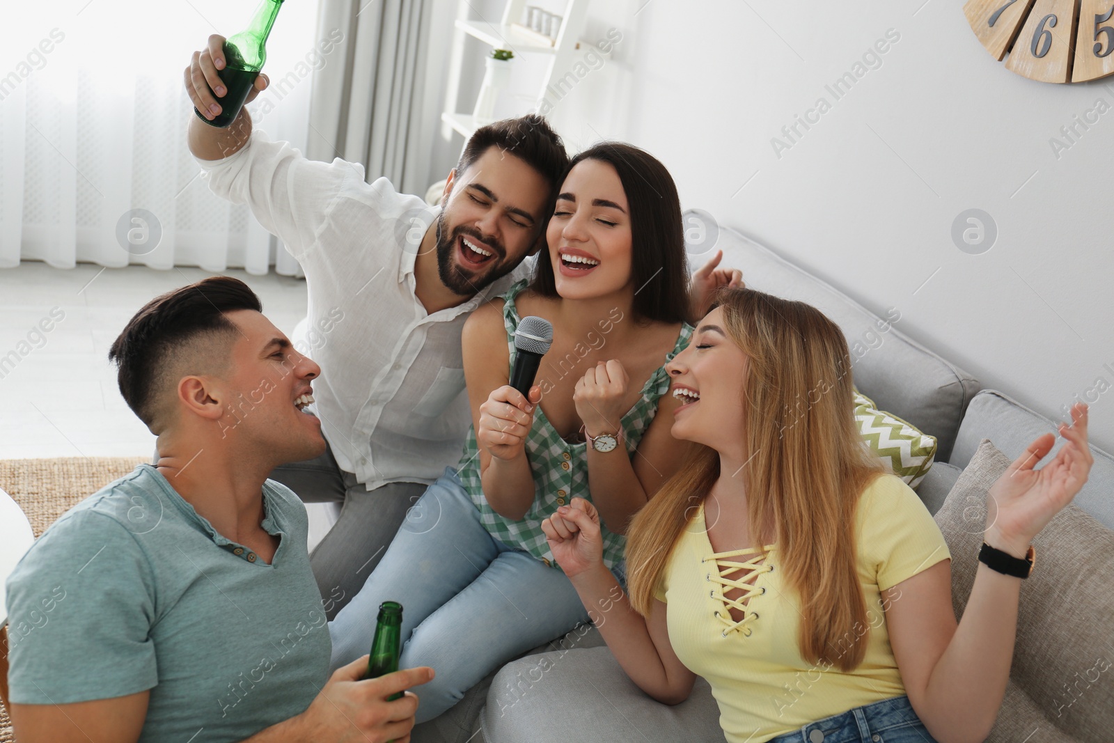 Photo of Happy friends singing karaoke together at home