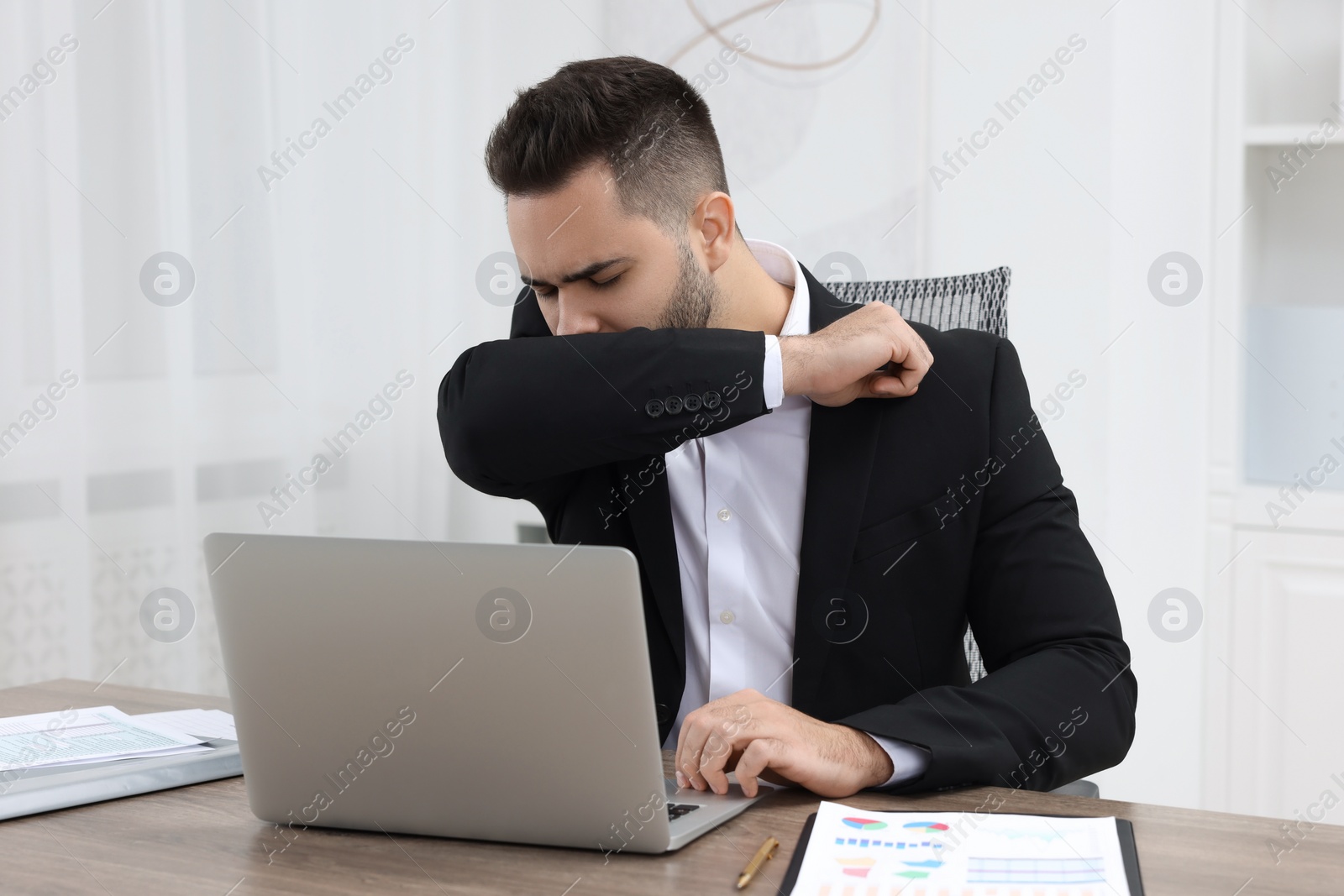 Photo of Sick man coughing at workplace in office