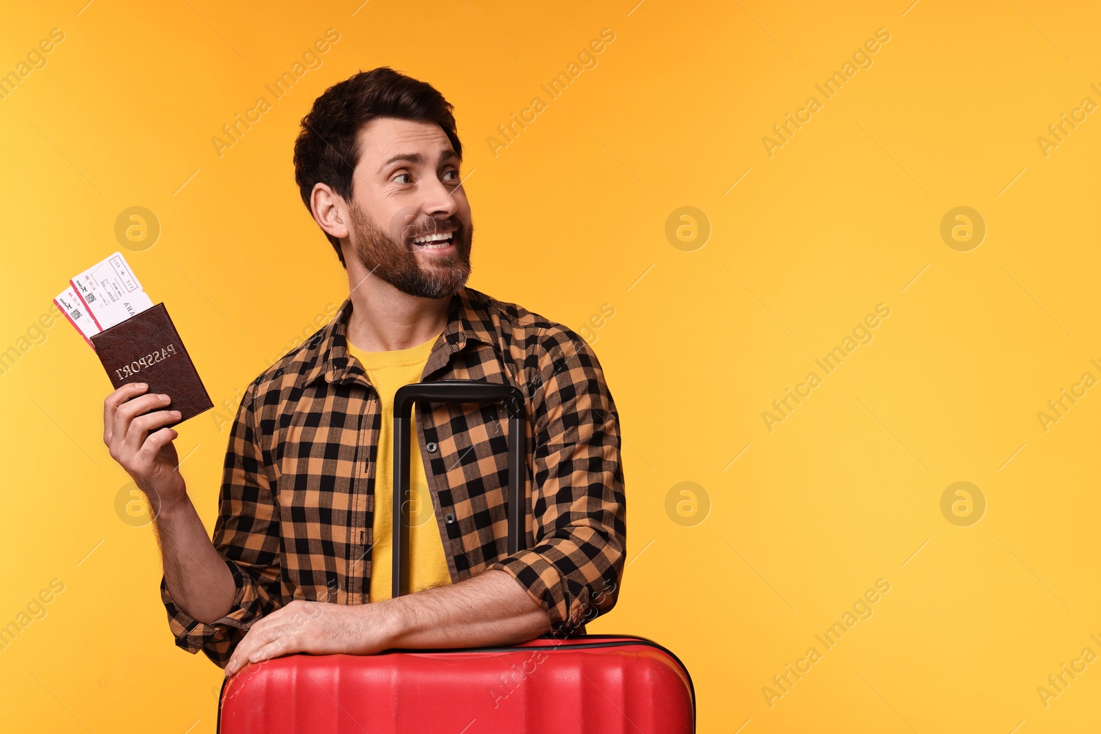 Photo of Smiling man with passport, tickets and suitcase on yellow background. Space for text