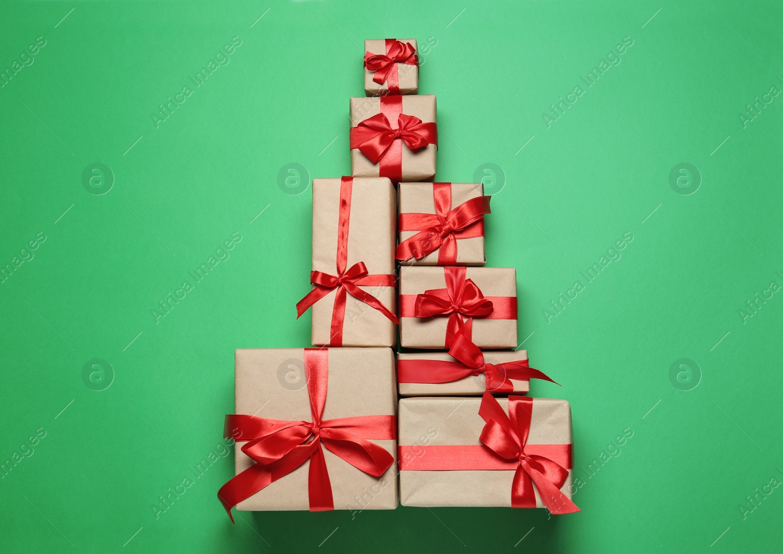 Photo of Christmas tree shape of gift boxes on green background, flat lay