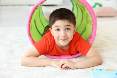 Cute little child in playing tunnel on floor, indoors