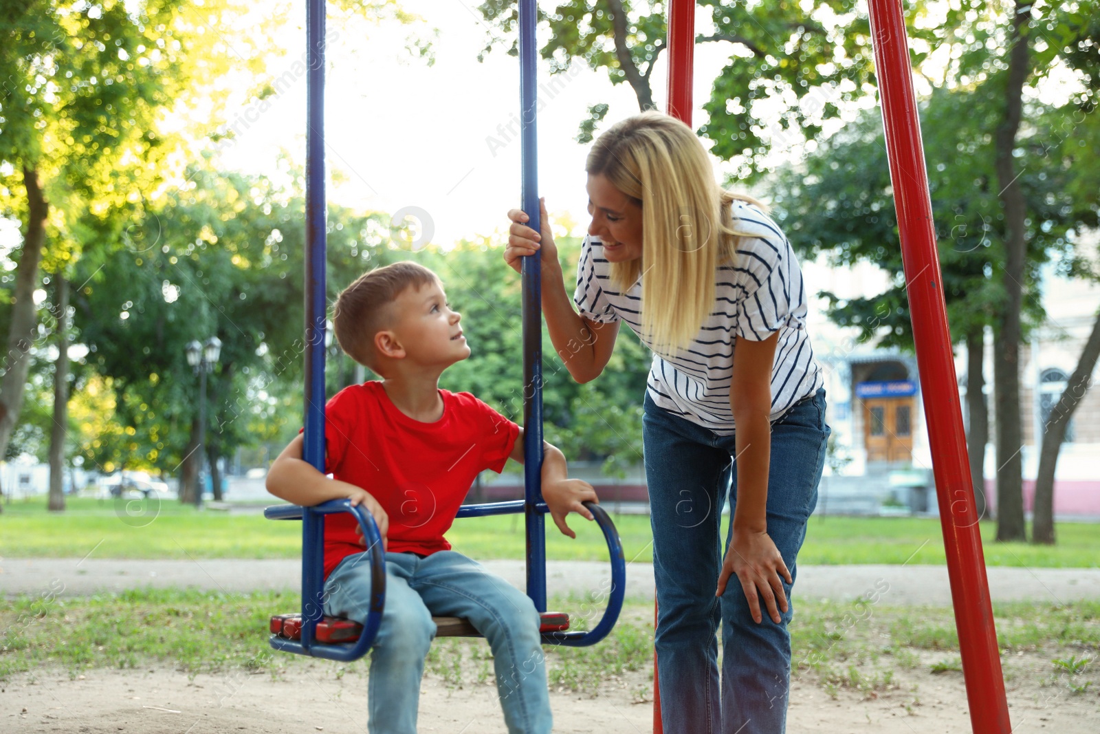 Photo of Nanny and cute little boy on swing in park