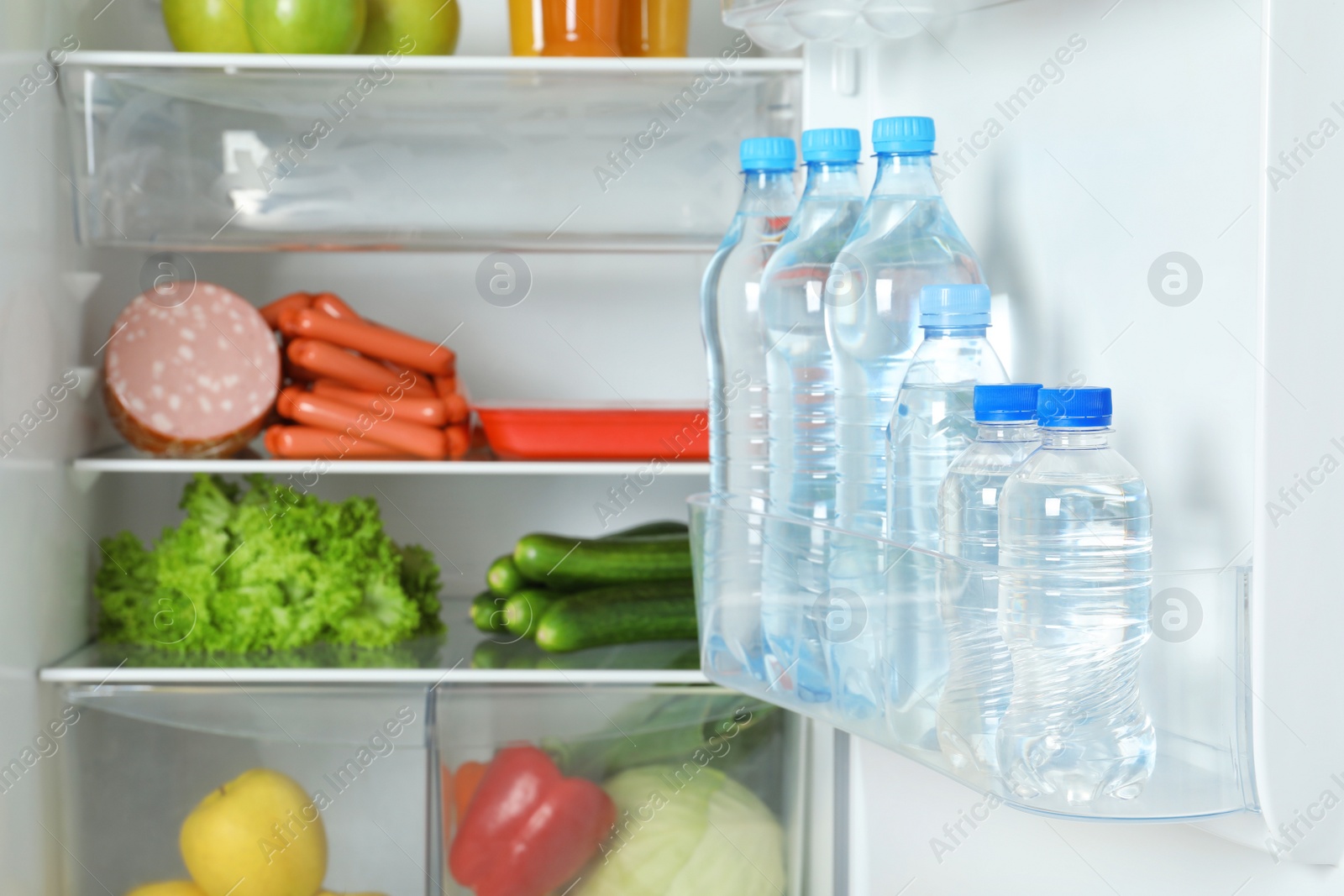 Photo of Bottles of water on refrigerator door shelf, closeup