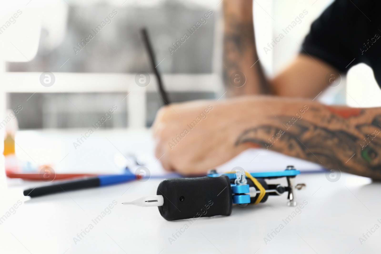 Photo of Professional tattoo machine and blurred master on background