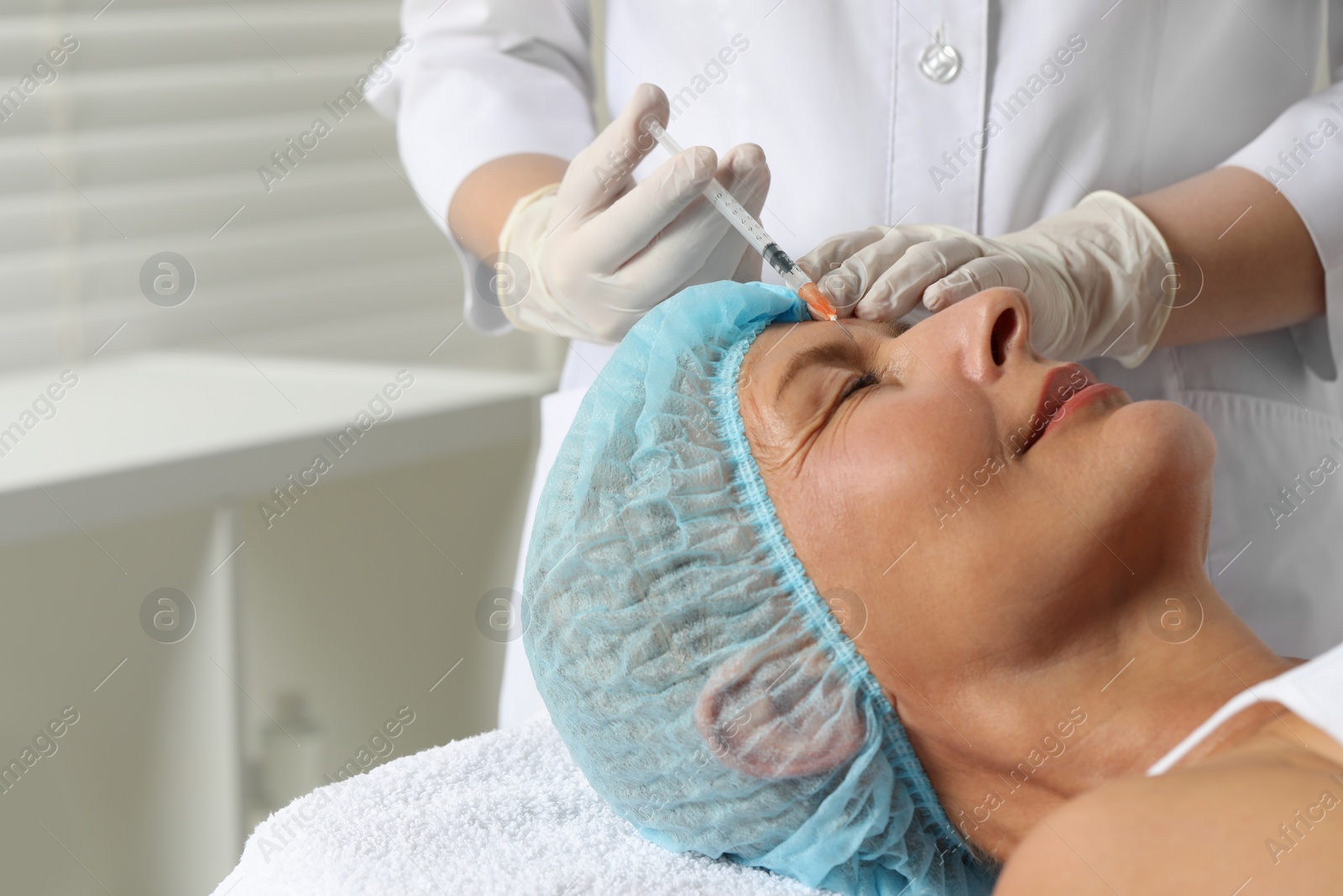 Photo of Doctor giving facial injection to senior woman in clinic, closeup. Cosmetic surgery