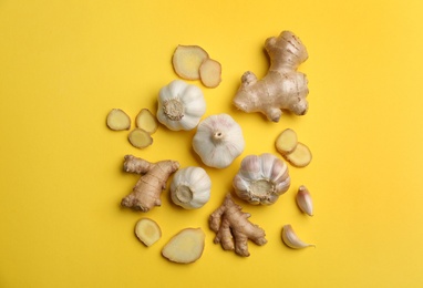 Photo of Ginger and garlic on yellow table, flat lay. Natural cold remedies